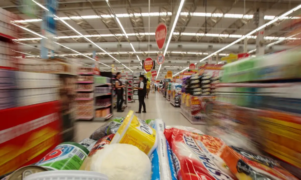 Carrinho de compras com alimentos em movimento no corredor de um supermercado