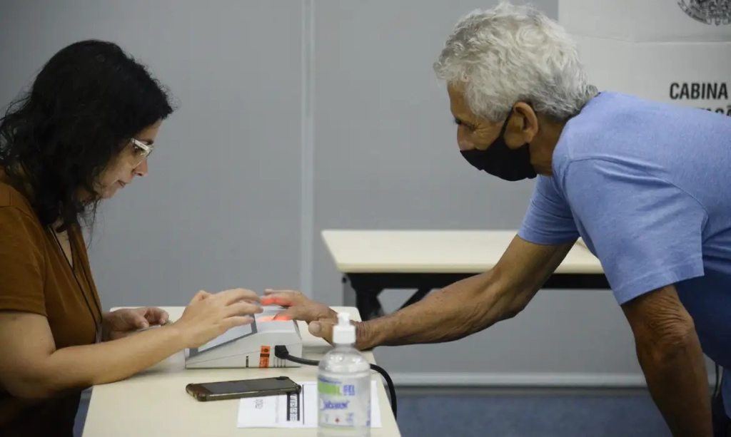 Eleitores em fila e votando em seção eleitoral montada em pavilhão no Rio de Janeiro